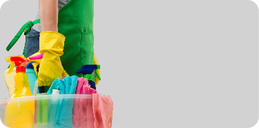 A person's gloved hand is holding a basket containing cleaning appliances.