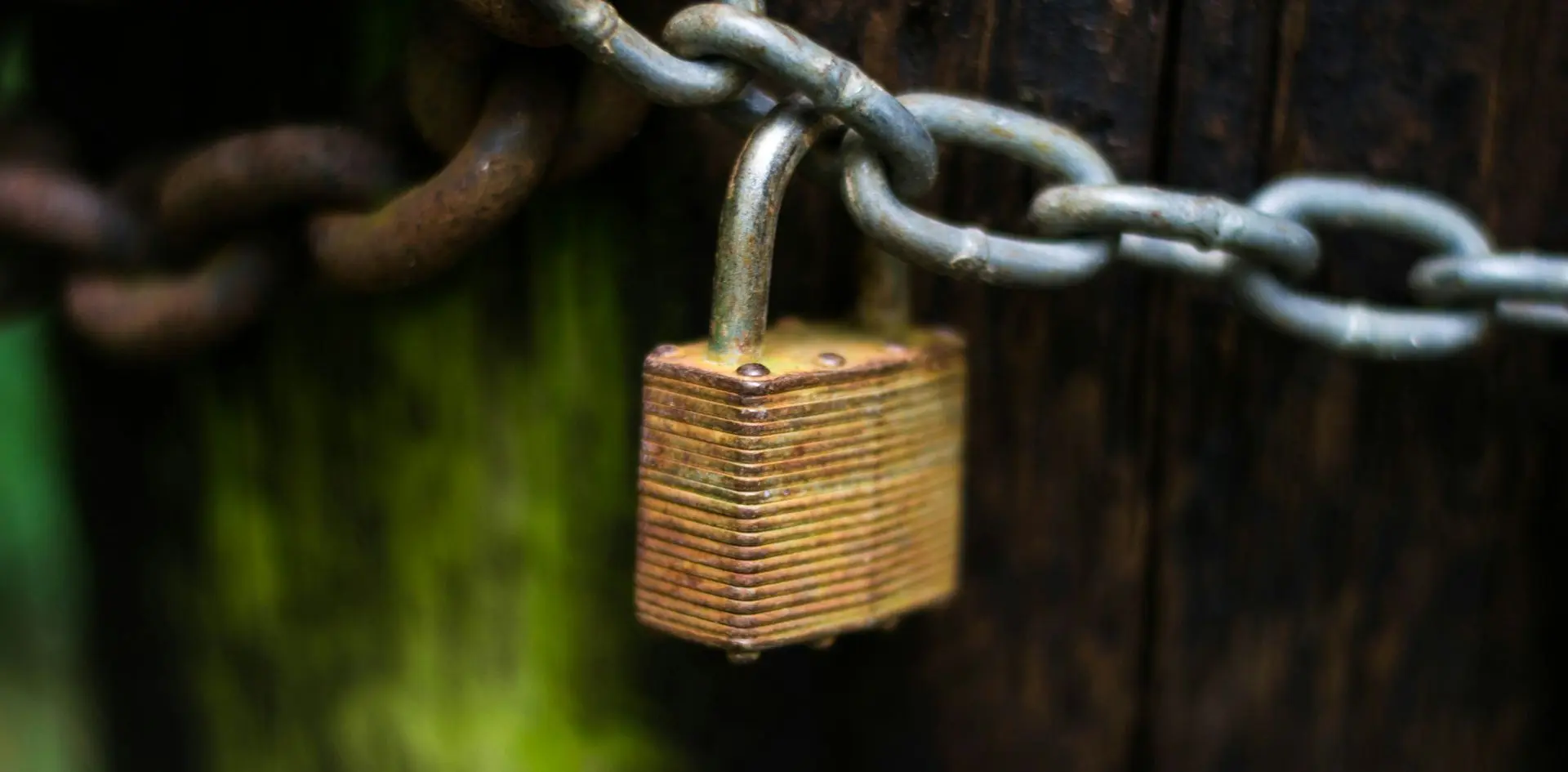 A lock hosited in one of the links of a metallic chain, representing an authetication framework.