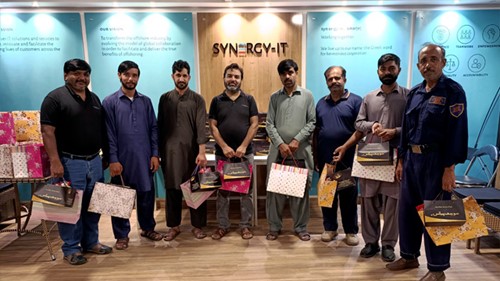 A group of people posing for a photo. They are all holding gift bags.